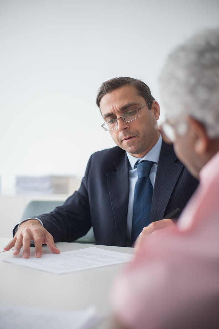 services-02 Senior man in discussion with consultant in office setting, reviewing documents.